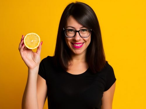 Lächelnd mit frischer Zitrone vor leuchtendem Studiohintergrund